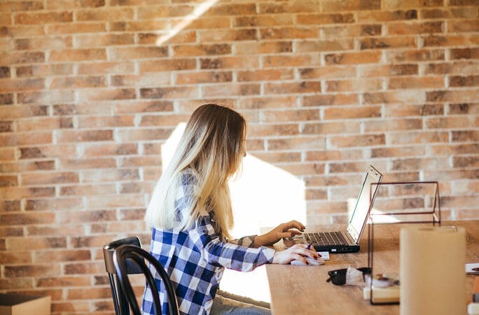 Solo founder typing a cold outreach email on a laptop at a startup desk